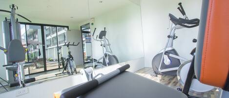 A gym with exercise equipment, a mirror, and a wooden floor.