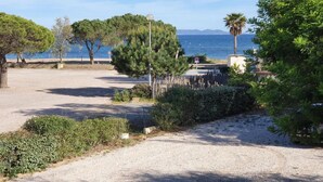 A coastal area with a gravel path, trees, and a view of the sea. - Apartment in Cavalaire near Sandy Beach (Cavalaire sur Mer)