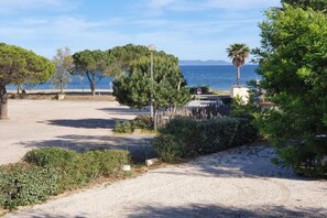 Eine Küstenlandschaft mit einem Kiesweg, Bäumen und Blick aufs Meer.