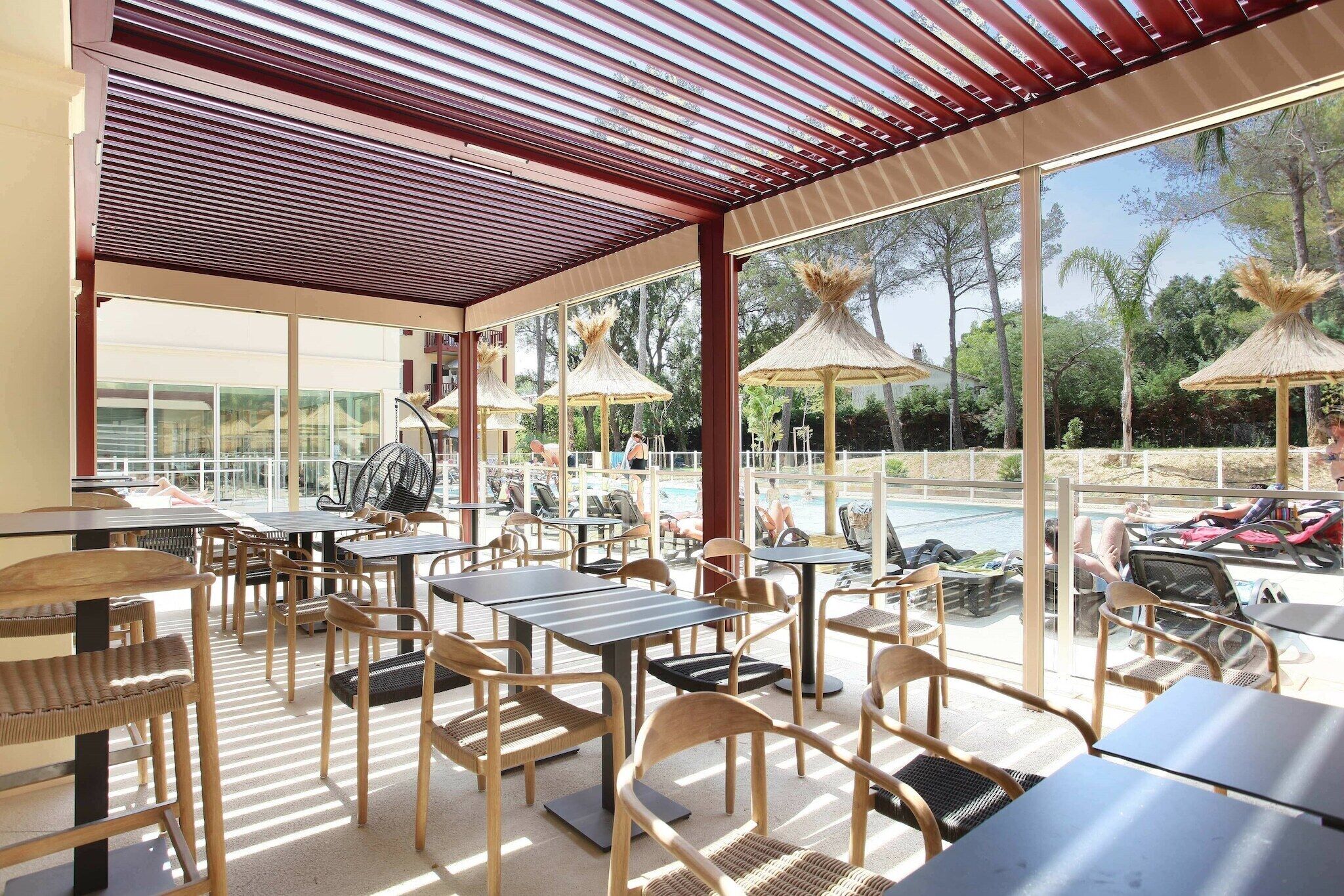 Un espace extérieur aménagé avec des tables et des chaises, une piscine et des parasols.