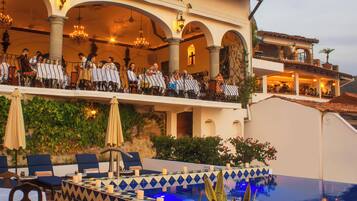 Un hotel con posti a sedere all'aperto, una piscina e una sala da pranzo con ospiti.