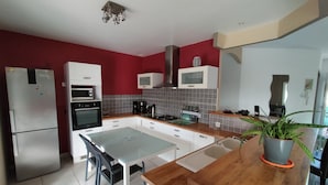A modern kitchen with white cabinets, a wooden countertop, a dining table, and a potted plant. - Soleil single-storey villa with 8/4 saltwater swimming pool, secure, fenced garden  (Lagorce)