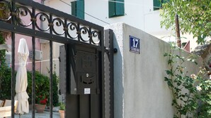 A gated entrance with a mailbox, a house number sign, and a potted plant. - Guest House Leta (Split)