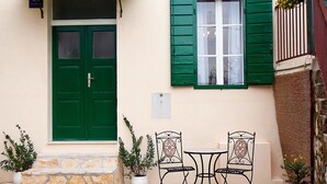 A quaint building with a green door and shutters, a small outdoor seating area with two chairs and a table, and potted plants. - Guest House Leta (Split)
