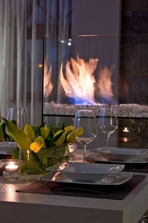 A dining table set with plates, glasses, and a centerpiece of yellow flowers.