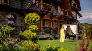 A large, multi-story stone building with balconies and a well-maintained garden.