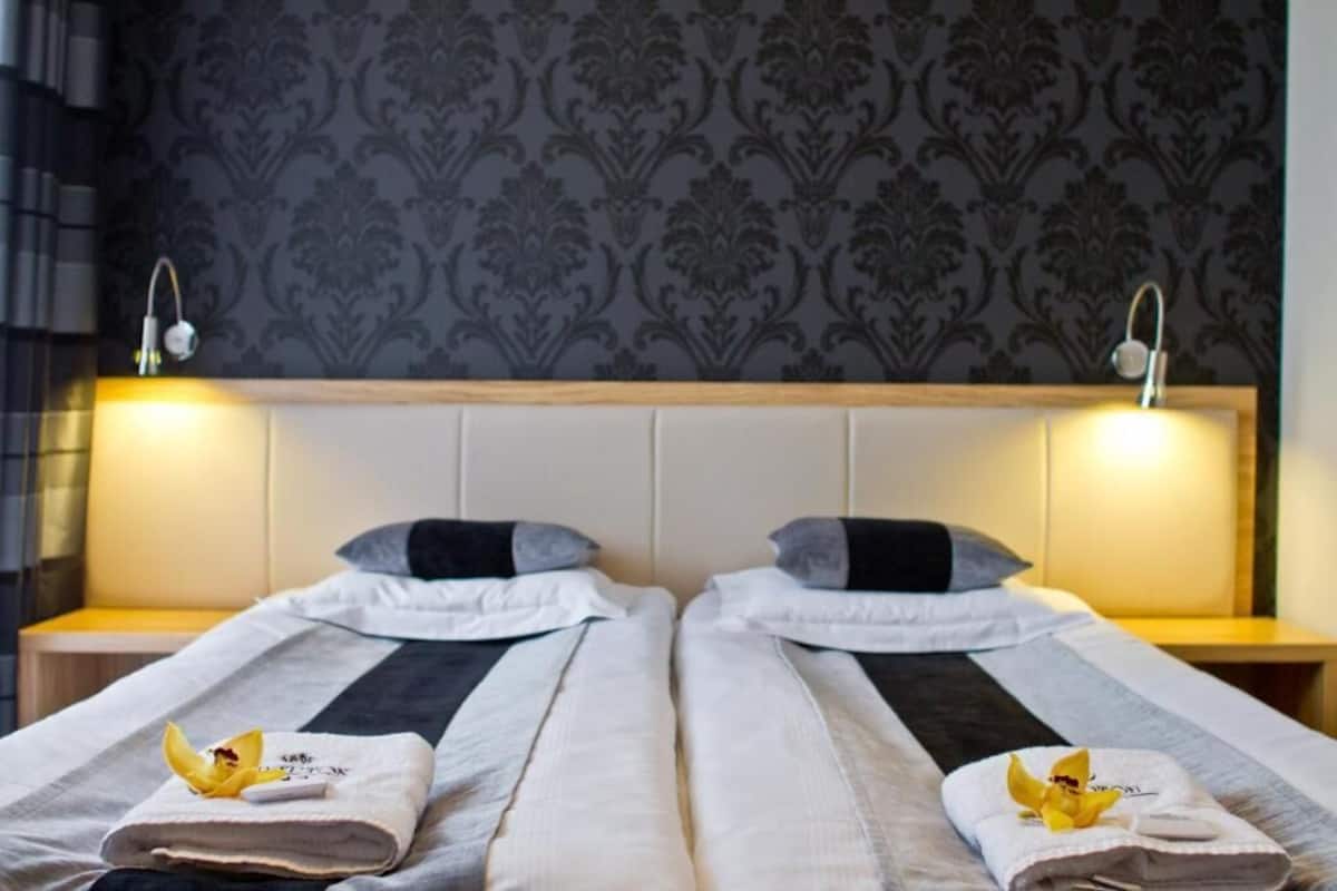 A double bed with a headboard, two bedside tables, and a patterned wallpaper.