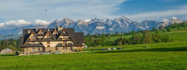 A chalet-style building with a stone facade, multiple gabled roofs, and a balcony.
