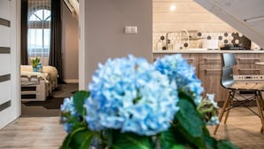A modern interior with a wooden floor, a kitchen with a hexagonal tile backsplash, and a dining area with a chair.