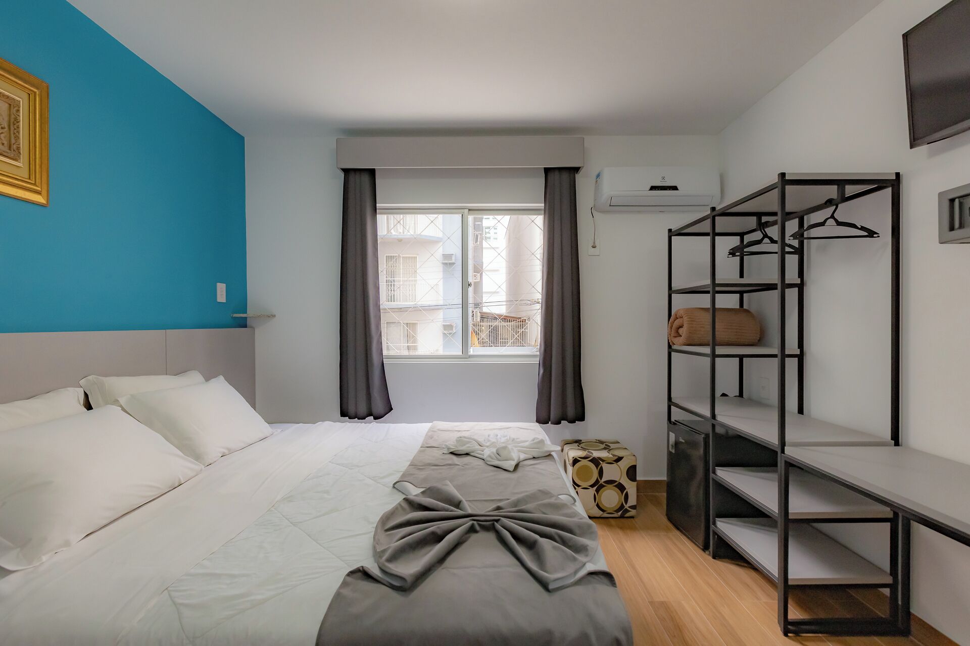 A bedroom with a bed, a window with curtains, a wardrobe, and a radiator.