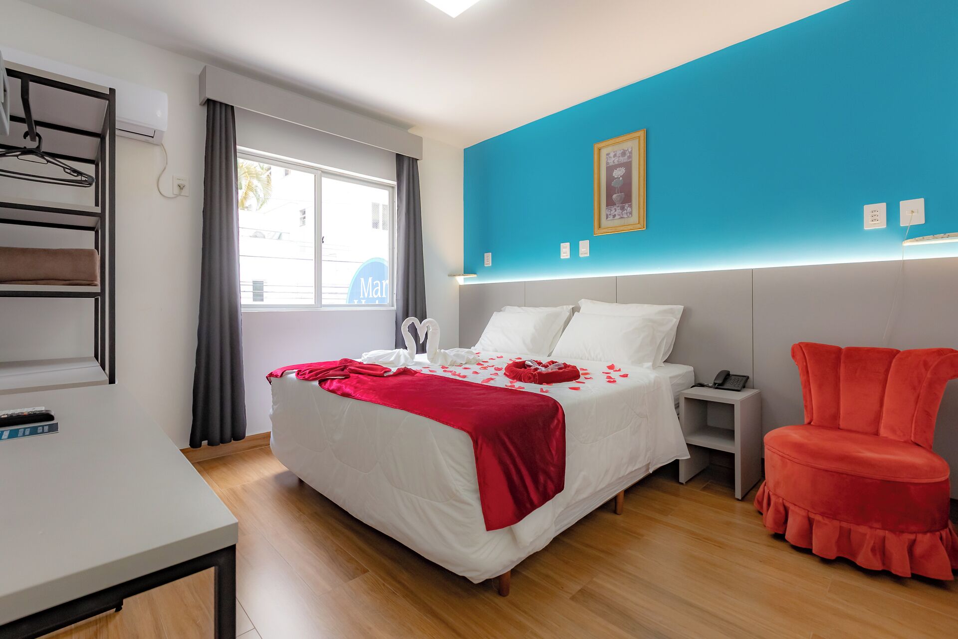 A modern hotel room with a bed, bedside table, and a red chair.