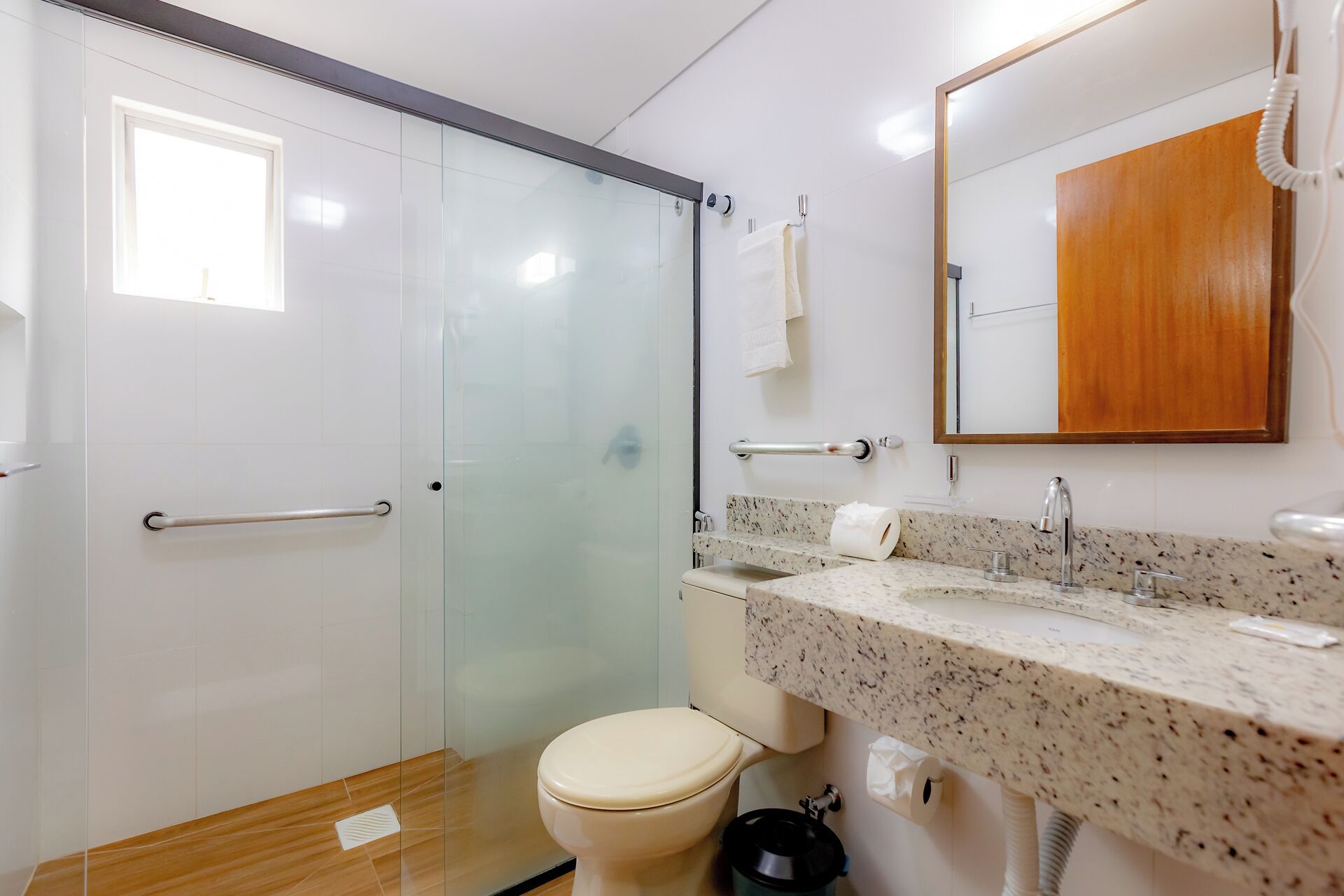 Un baño moderno con cabina de ducha de vidrio, inodoro y lavamanos con encimera de mármol.