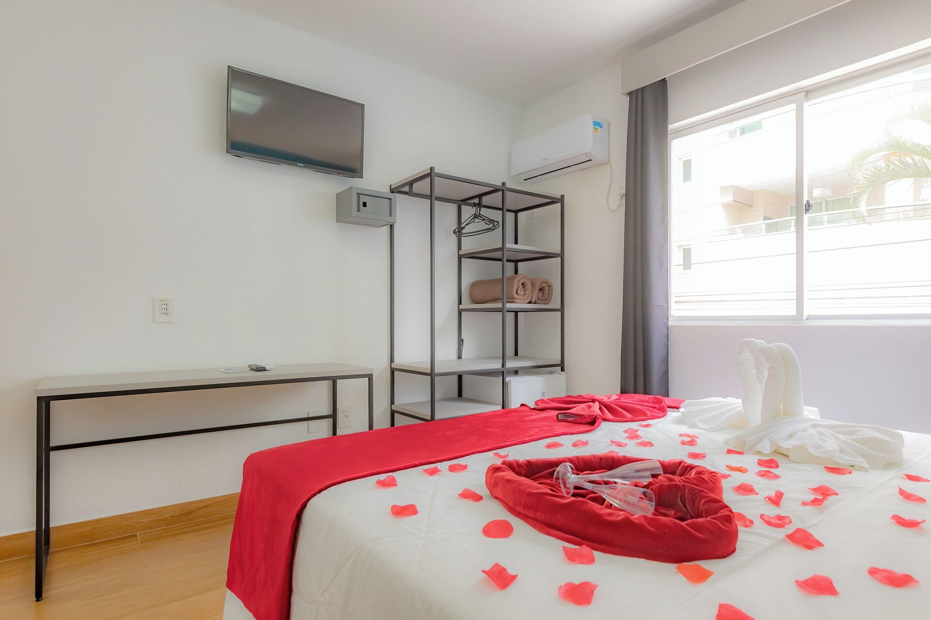 A hotel room with a bed, a TV, a wardrobe, and a window with curtains.