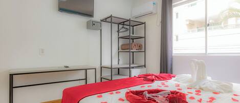 A hotel room with a bed, a TV, a wardrobe, and a window with curtains.
