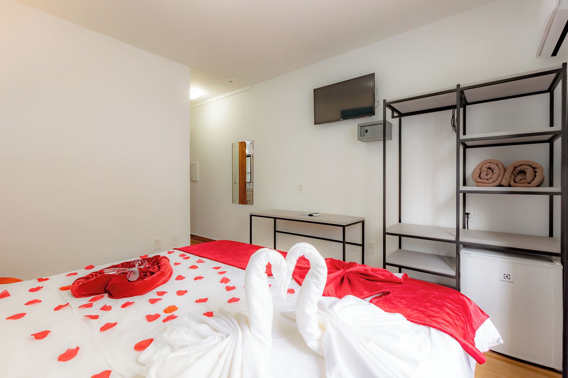 A hotel room with a bed, a TV, a desk, and a built-in wardrobe.