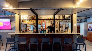 Zona de bar con mostrador, taburetes y un bartender.