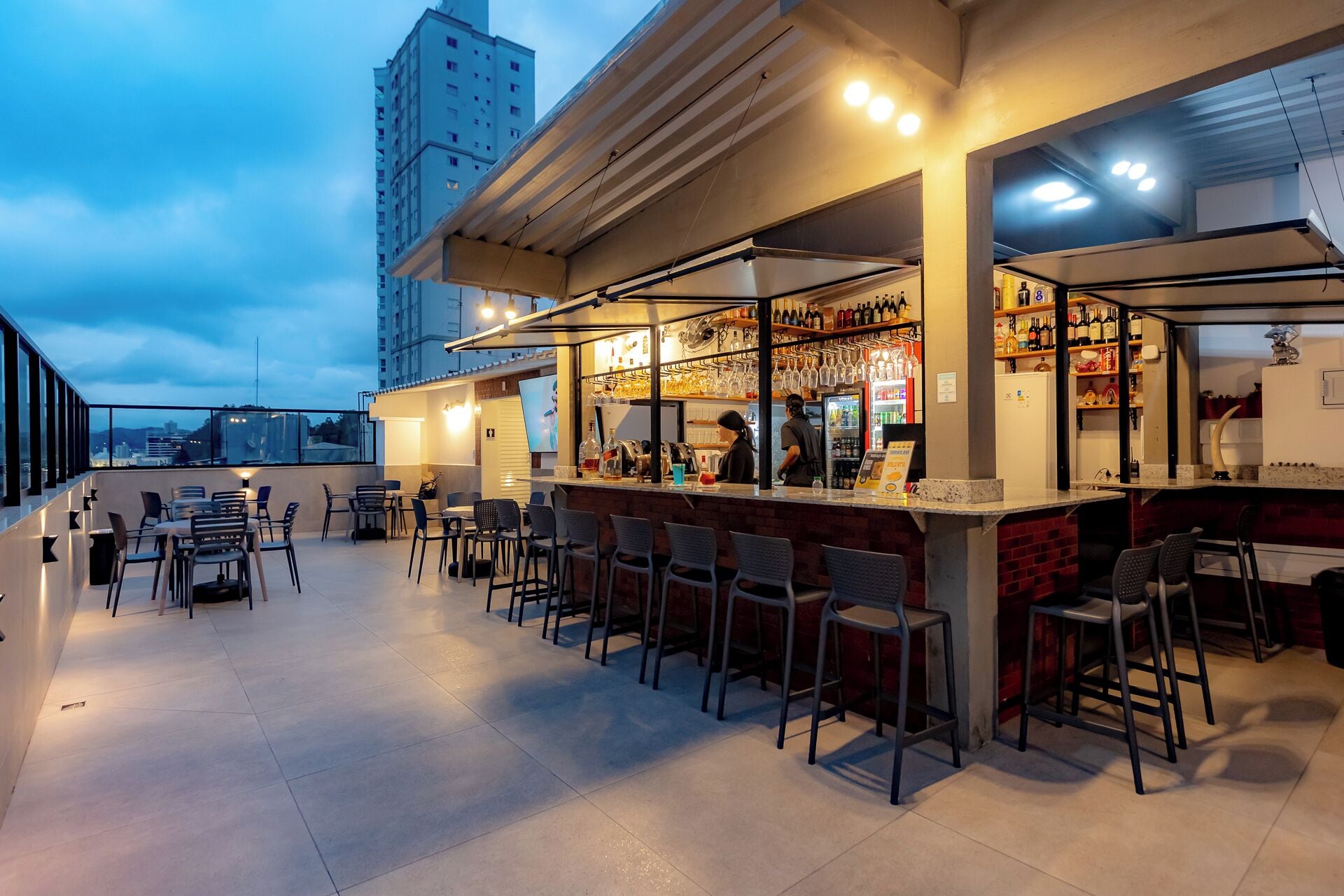 An outdoor bar area with seating and a bartender.