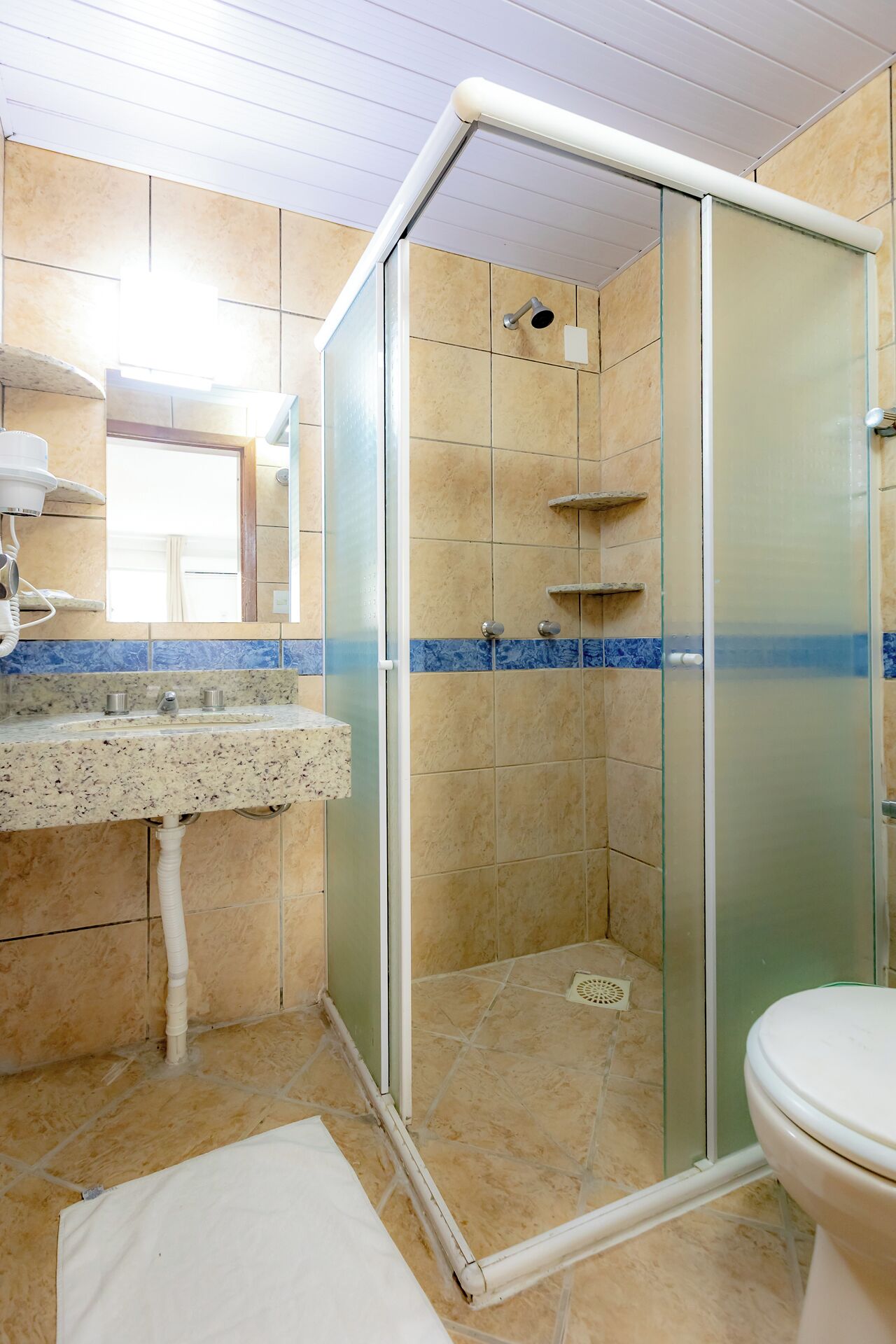 A bathroom with a glass-enclosed shower, a sink with a marble countertop, and a toilet.