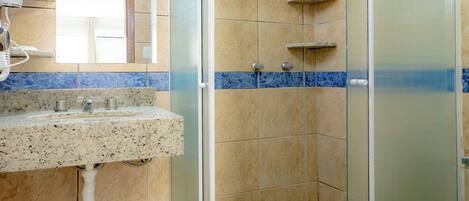 A bathroom with a glass-enclosed shower, a sink with a marble countertop, and a toilet.