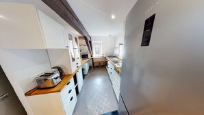 A narrow kitchen with white cabinets, a wooden countertop, a built-in microwave, and a refrigerator. - spacious duplex near petite france up to 4 (Strasbourg)