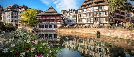 A traditional European town with half-timbered buildings, a canal, and a bridge.