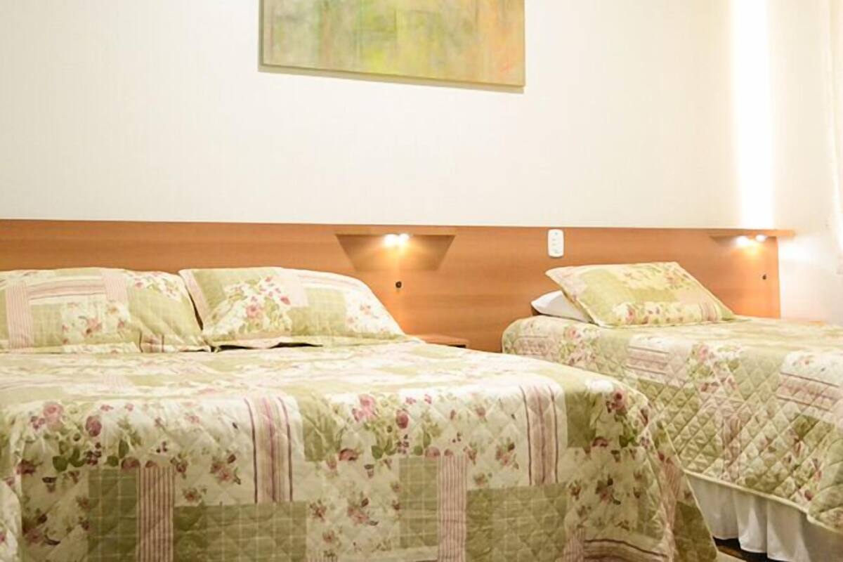 Habitación de hotel con dos camas, cabecero de madera, aire acondicionado de pared y un cuadro.