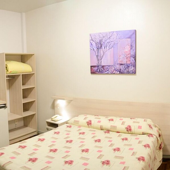 A bedroom with a bed, a nightstand, a wardrobe, and a painting on the wall.