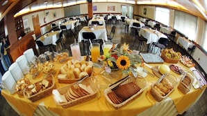 A buffet setup with various food items and beverages, arranged on a table with a yellow tablecloth. - Pampa Hotel (Vacaria)
