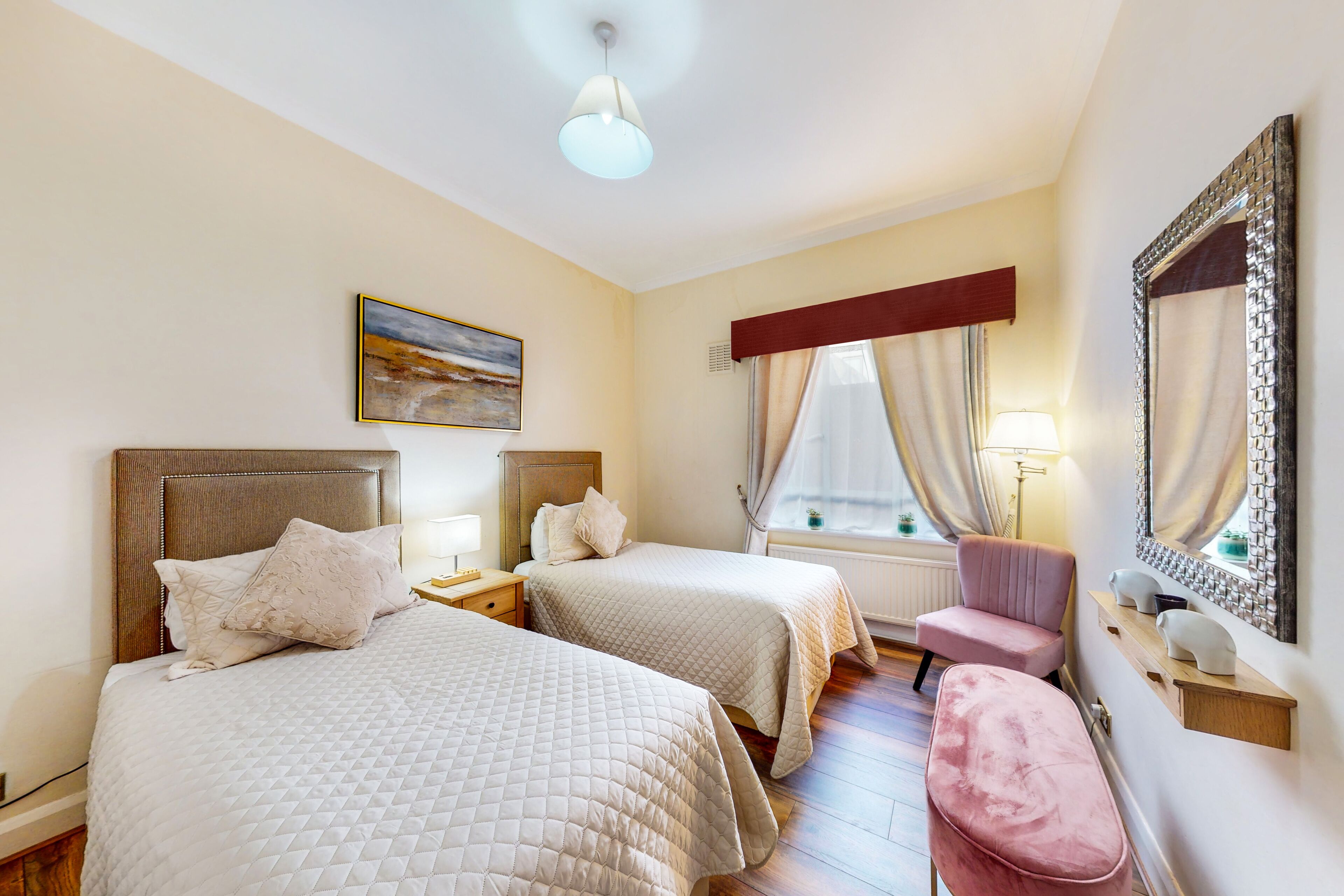 Habitación de hotel con dos camas, una silla, un espejo y un cuadro en la pared.