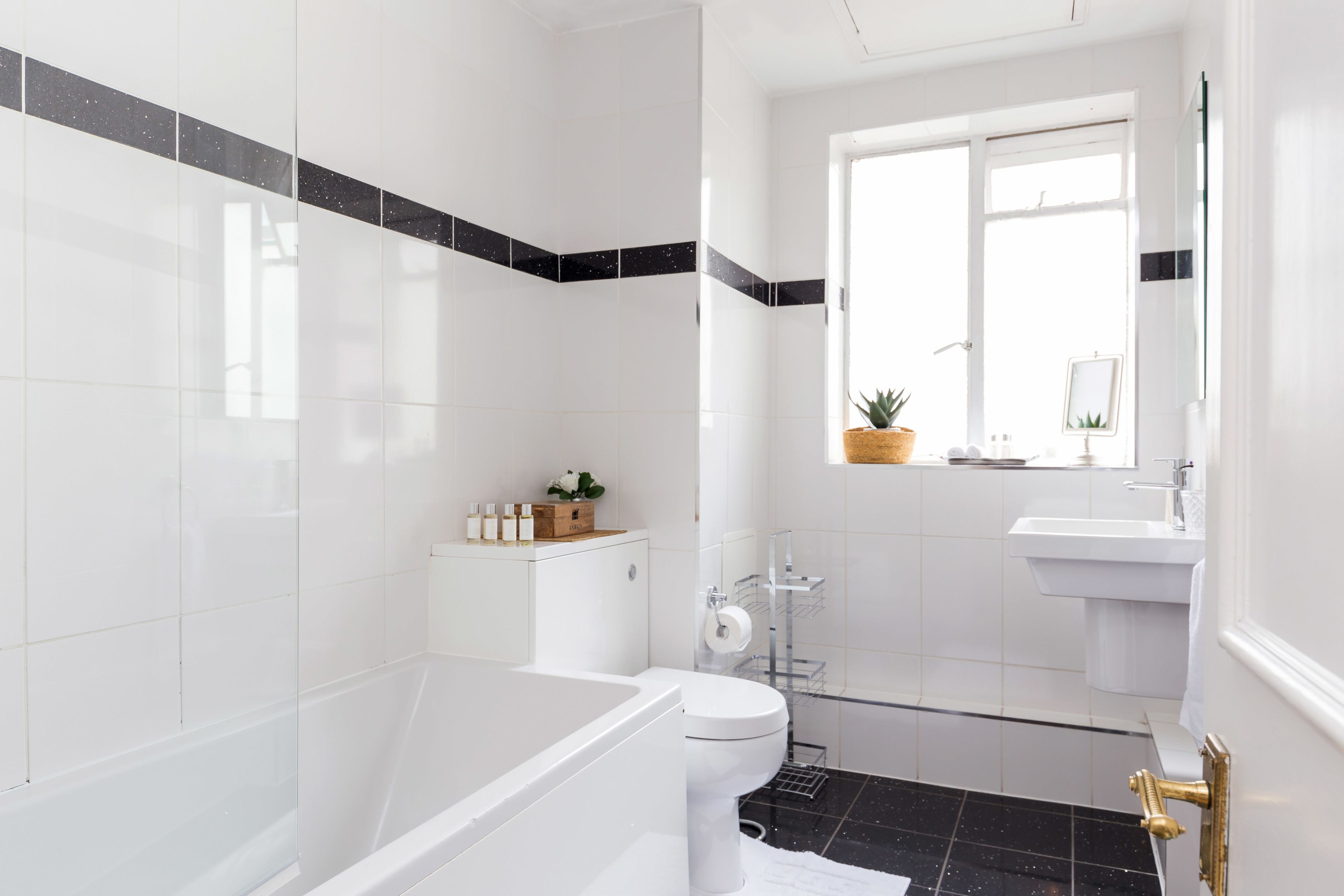 Een moderne badkamer met een bad, toilet en wastafel.