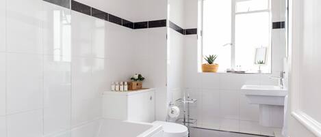 Een moderne badkamer met een bad, toilet en wastafel.
