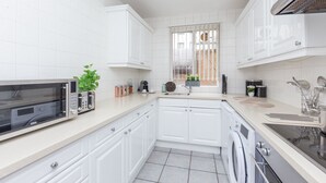 Een moderne keuken met witte kasten, een ingebouwde magnetron, een koffiezetapparaat en een raam met uitzicht.