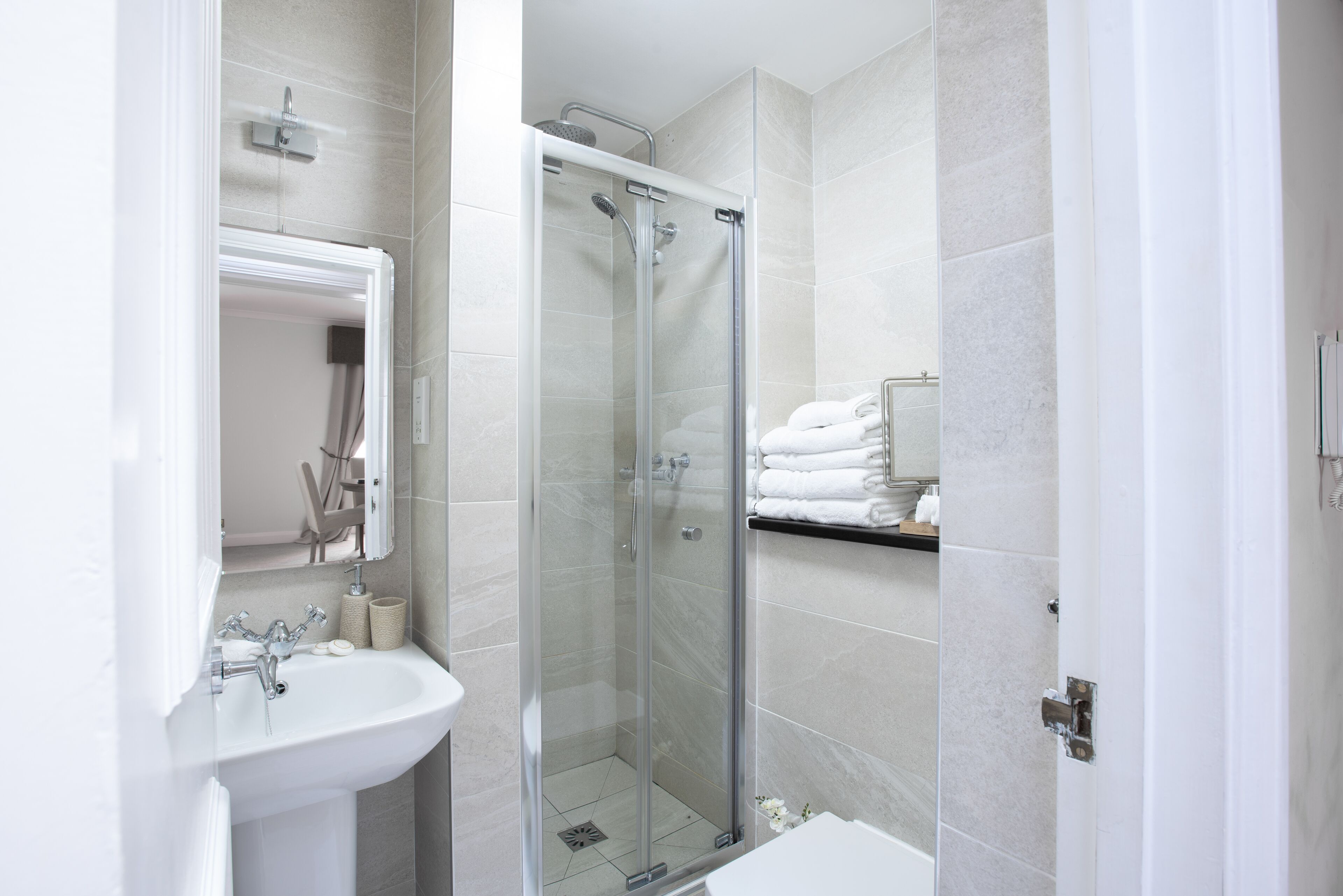 Un baño moderno con ducha envuelta en vidrio, un lavabo e inodoro.