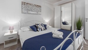Une chambre moderne avec un grand lit, des murs blancs et un tableau accroché au-dessus.