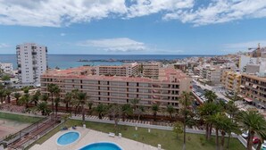 Un hotel con diversi piani, una piscina e vista sul mare e sulla città.