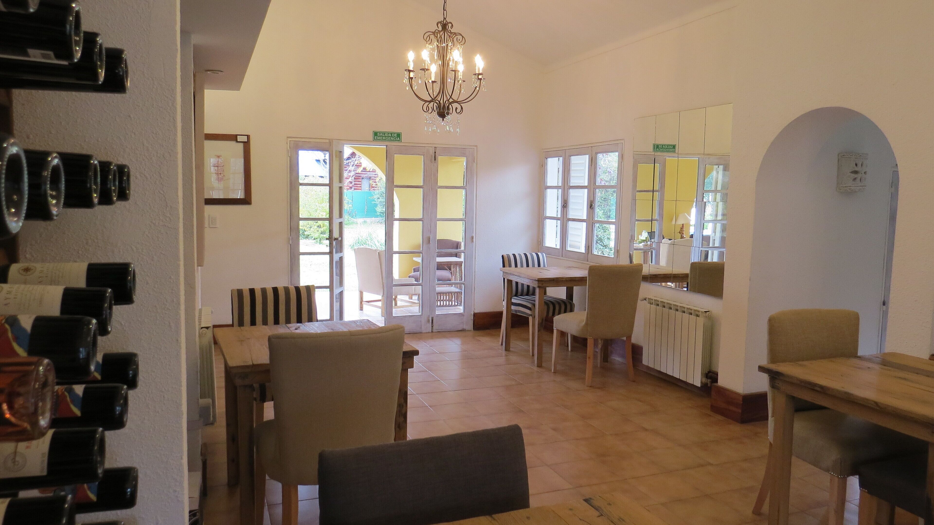 Un espace repas agrémenté d’un lustre, de tables, de chaises et offrant une vue sur l’extérieur grâce à de grandes fenêtres.