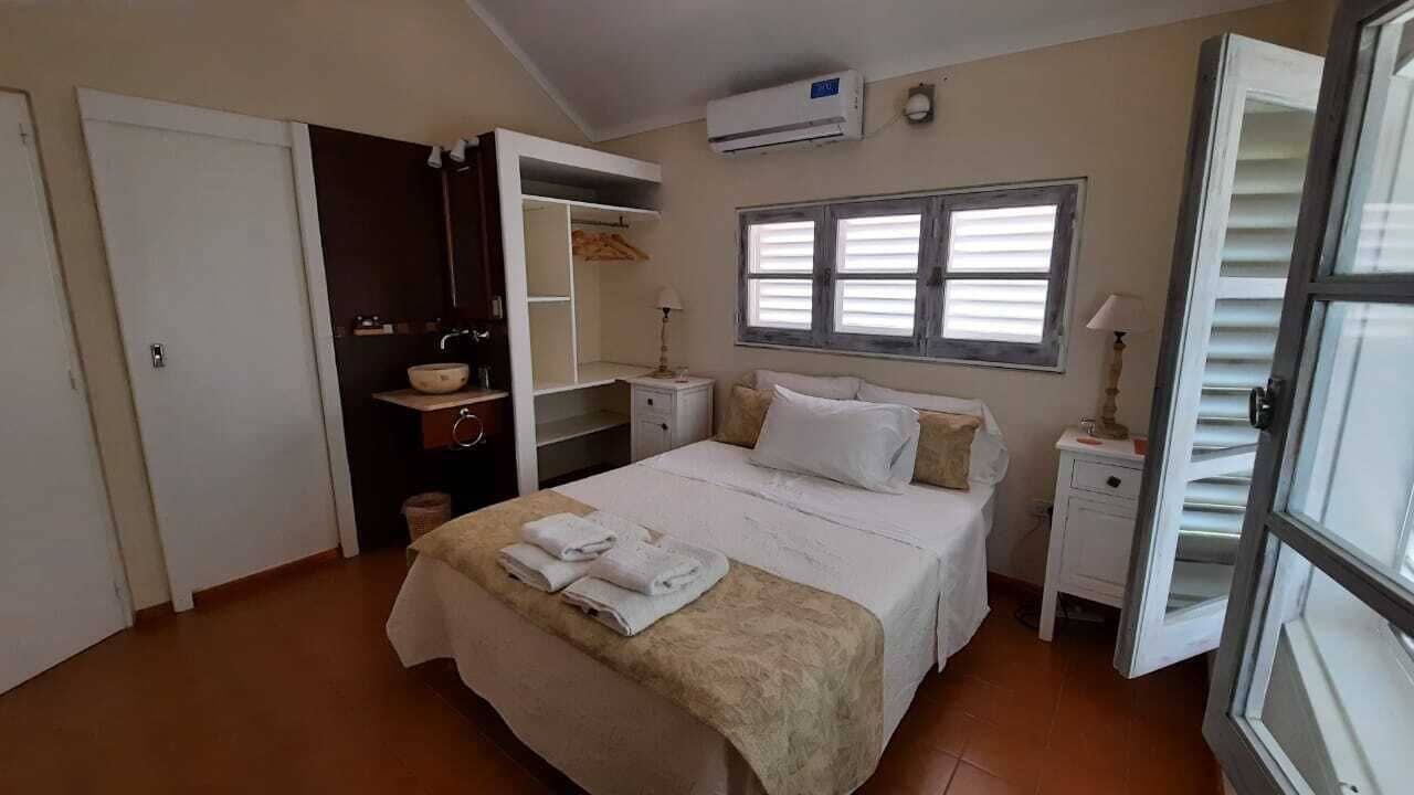 A bedroom with a bed, a wardrobe, a bedside table, and a window.