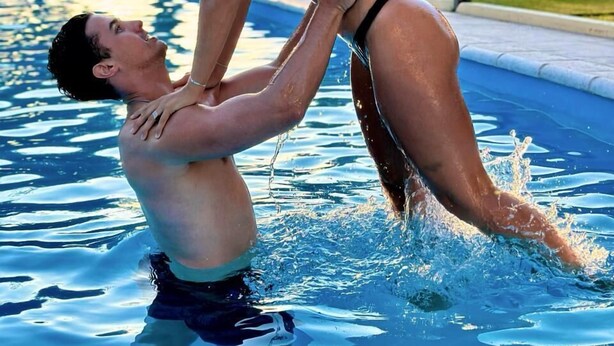 A man and a woman in a swimming pool, with trees and a white structure in the background. - La Masía Hotel Boutique (Chacras de Coria)