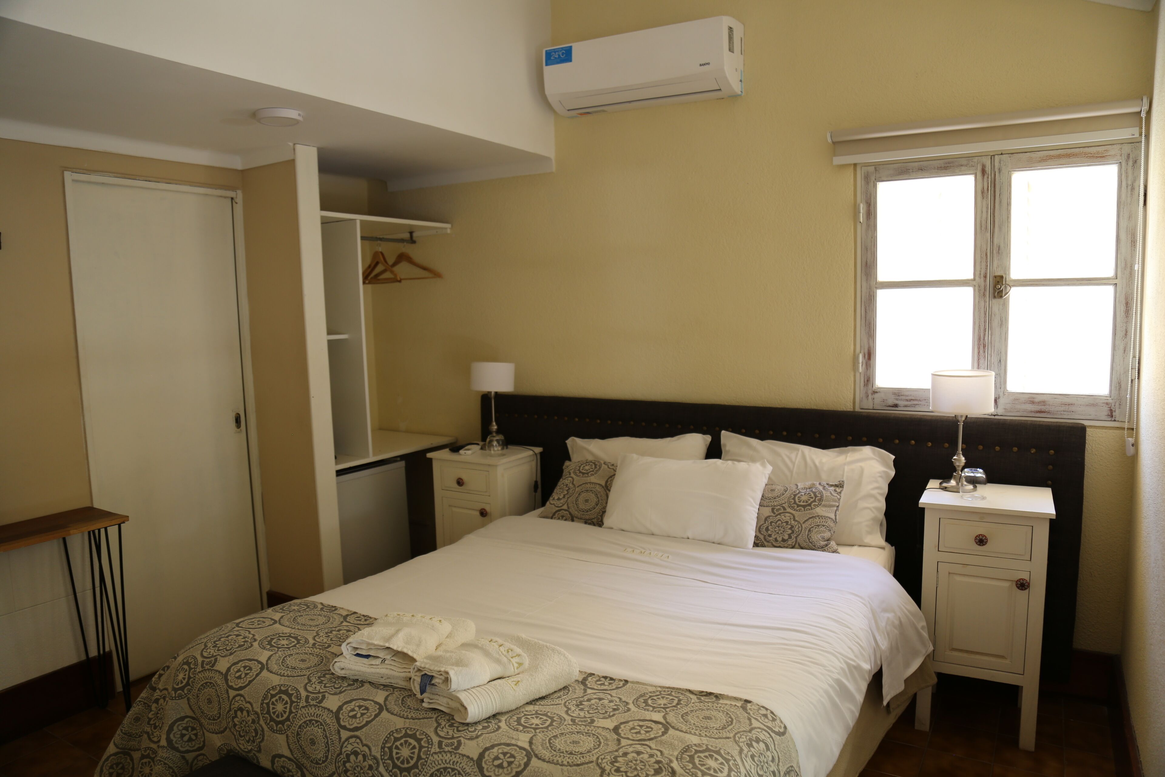 Une chambre à coucher comprenant un lit, des tables de chevet, une armoire et un appareil de climatisation.