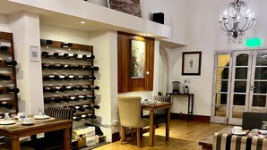 A dining area with a wooden table set for four, surrounded by chairs. A wine rack with bottles is visible in the background. - La Masía Hotel Boutique (Chacras de Coria)