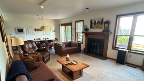 Un salón amplio con chimenea, asientos cómodos y un ventanal que proporciona luz natural.