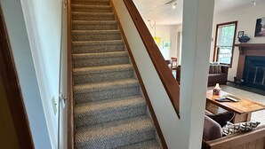 Una escalera alfombrada con barandilla de madera que conduce a una sala de estar.