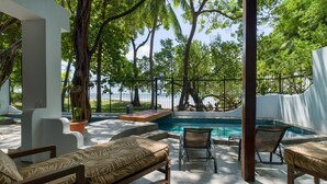 An outdoor pool area with lounge chairs and a view of the sea. - Casa Woodbine Beachfront House (Tamarindo)