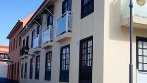Un edificio de varios pisos con balcones, techo de tejas y una farola.
