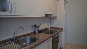 Cocina con encimeras de granito, pileta de acero inoxidable y horno empotrado.