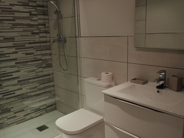 Un baño moderno con ducha, inodoro y lavamanos.
