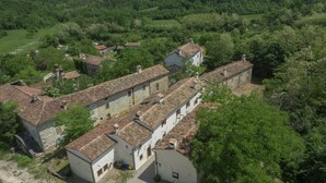 A traditional stone building with a tiled roof, surrounded by lush greenery and other stone buildings. - Traditional Stone House 3 (Buzet)