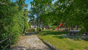 A park pathway with a wooden fence on one side and a playground with a slide in the distance. - Traditional Stone House 3 (Buzet)