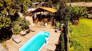 Eine Holzterrasse mit Schwimmbad, Liegestühlen und einer überdachten Sitzgruppe.