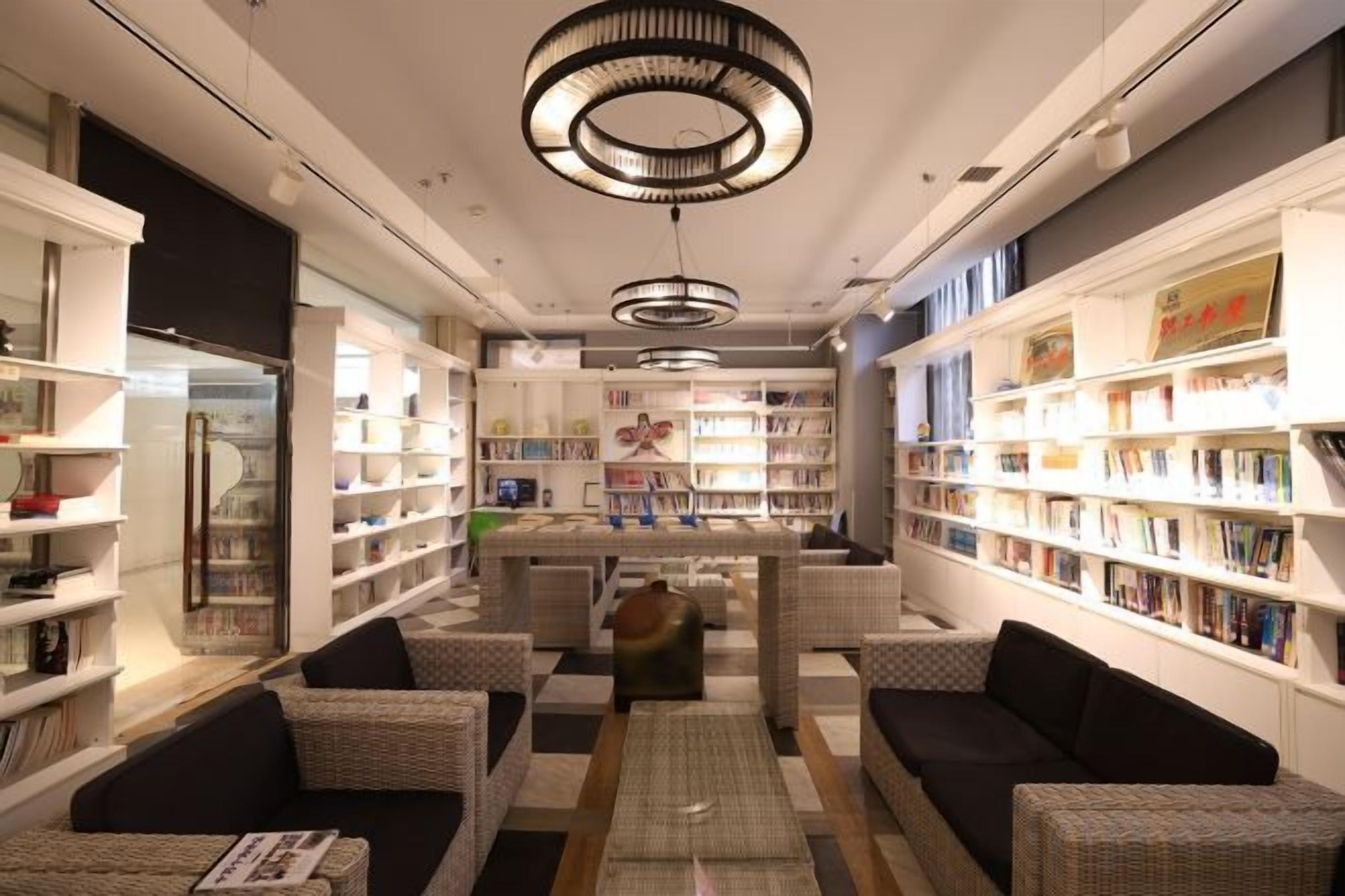 Eine Bibliothek mit Bücherregalen, Sitzbereichen und einem zentralen Tisch.